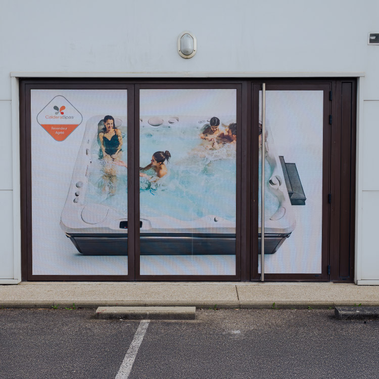 Vitrophanie microperforée appliquée sur la façade d’un commerce, laissant passer la lumière.