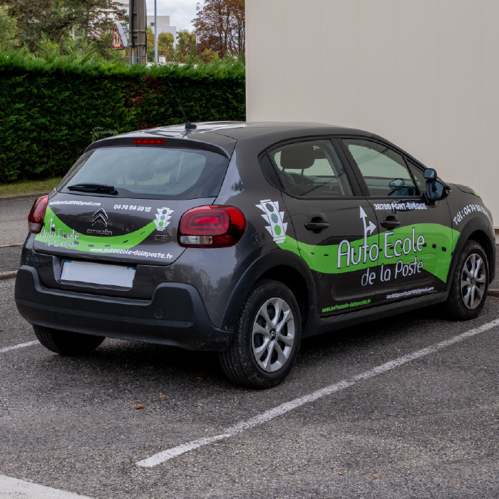 Arrière d’une voiture de l’Auto-École de La Poste floquée avec un marquage personnalisé réalisé à Lyon.