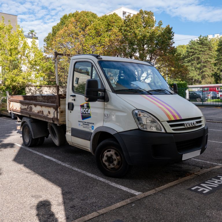 Camion plateau BCCA floqué avec bandes colorées et logo de l’entreprise.