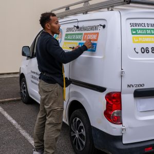 Technicien Persecom posant l’adhésif latéral sur l’utilitaire BGC à Lyon.