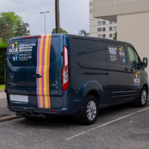 Fourgon bleu BCCA floqué avec bandes colorées et marquage arrière.