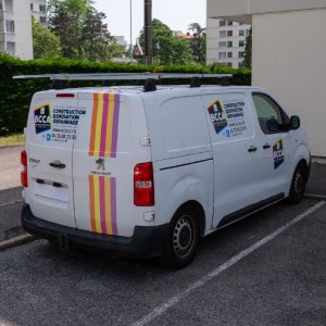 Utilitaire blanc BCCA floqué avec bandes graphiques verticales et logo de la société.