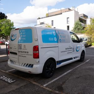 Utilitaire ArtNet floqué avec panneaux bleus, pictogrammes et coordonnées, installé à Meyzieu.