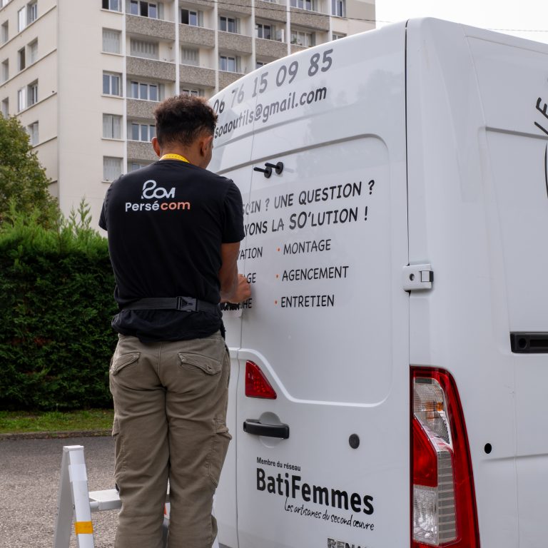 Installateur Persecom posant le marquage à l’arrière d’un véhicule utilitaire sur Lyon.