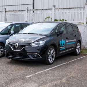 Berline noire Direct Trans floquée, stationnée sur un parking à Vénissieux.