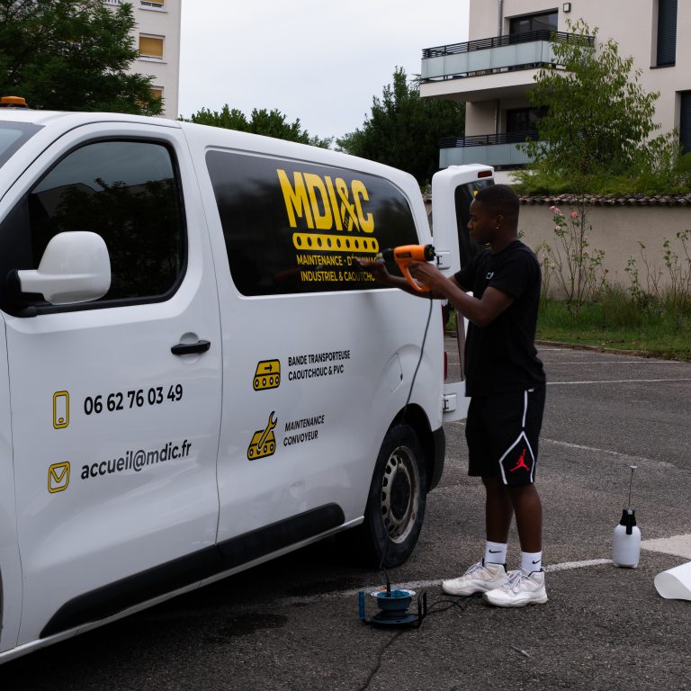 Installateur Persecom appliquant le marquage adhésif de la société MDIC à Lyon.