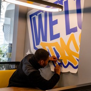 Installateur Persecom posant un adhésif mural dans le restaurant Enjoy Tacos.