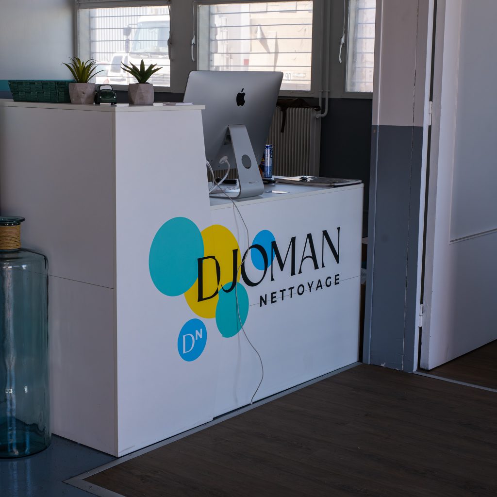 Logo adhésif Djoman Nettoyage appliqué sur le comptoir d’accueil du garage.